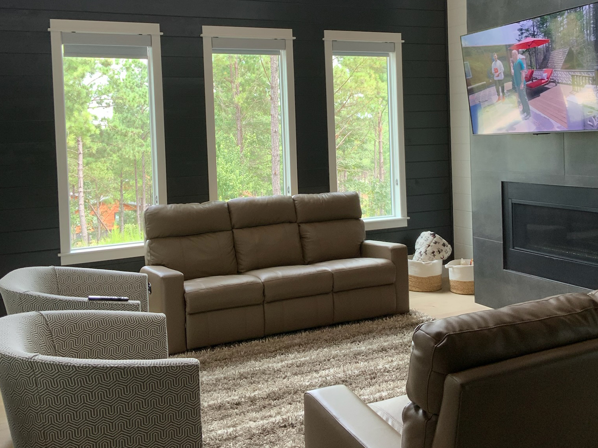 Step into an inviting living room featuring two luxurious leather reclining sofas, two stylish swivel barrel chairs, and a captivating 65" Smart TV—an ideal space for relaxed family evenings or lively gatherings.